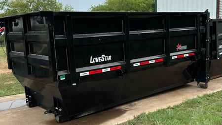 A large black dumpster is parked on the side of the road.
